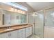 Bright bathroom featuring double sinks, a large mirror, and walk-in shower at 26034 Oakmount Dr, Leesburg, FL 34748