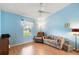 Comfortable bedroom with light blue walls, wood-look flooring, and a large window for natural light at 26034 Oakmount Dr, Leesburg, FL 34748