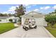 Charming single-story home featuring a well-maintained lawn, white siding, and a convenient golf cart parked in the driveway at 26034 Oakmount Dr, Leesburg, FL 34748