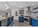 Contemporary kitchen with stainless steel appliances, custom blue cabinets, and open shelving at 2849 Doe Run Trl, Orange City, FL 32763