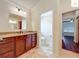 Bathroom vanity featuring a granite countertop, wooden cabinets, and a tile floor, with views into the toilet room and bedroom at 2994 Adrienne Way, The Villages, FL 32163
