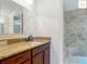 Bathroom vanity featuring a granite countertop, wooden cabinets, and a tiled shower at 2994 Adrienne Way, The Villages, FL 32163