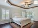 Bedroom with hardwood floors, tray ceiling, ceiling fan, and sliding glass doors at 2994 Adrienne Way, The Villages, FL 32163
