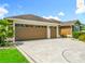 Exterior shot featuring home's three-car garage and decorative driveway; surrounded by manicured landscaping at 2994 Adrienne Way, The Villages, FL 32163