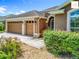 Close up exterior highlighting the three-car garage, complemented by beautiful landscaping and decorative stone at 2994 Adrienne Way, The Villages, FL 32163