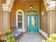 Charming front porch with a decorative bench, lush plants, and a teal-colored front door at 2994 Adrienne Way, The Villages, FL 32163