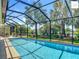 Screened-in pool with clear blue water surrounded by lush landscaping and an outdoor seating area at 2994 Adrienne Way, The Villages, FL 32163