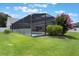 The backyard is equipped with a large screened-in pool, grassy area, and well-manicured flower garden at 3128 Ibis Hill St, Clermont, FL 34714