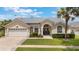 Inviting single-story home featuring a manicured lawn, arched windows, and an attached two-car garage at 3128 Ibis Hill St, Clermont, FL 34714
