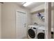 Laundry room with white washer and dryer, shelving and a door to the outside at 3128 Ibis Hill St, Clermont, FL 34714
