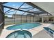 An inviting pool and jacuzzi are enclosed in a screen, with lounge seating and partially shaded patio at 3128 Ibis Hill St, Clermont, FL 34714