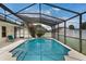 An inviting pool and jacuzzi are enclosed in a screen, with lounge seating and a flowering tree at 3128 Ibis Hill St, Clermont, FL 34714