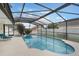 An inviting pool and jacuzzi are enclosed in a screen, with lounge seating and a flowering tree at 3128 Ibis Hill St, Clermont, FL 34714