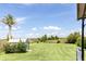 Manicured backyard featuring lush green lawn and shed under a sunny sky with scattered clouds at 31636 Gladys Ln, Tavares, FL 32778