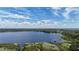 An aerial view of the lake with a vegetated shoreline, trees, and a bright blue sky with scattered clouds at 31636 Gladys Ln, Tavares, FL 32778
