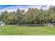 Spacious backyard with green grass, mature trees, white fence, and a barn at 32025 Timberlake Dr, Mount Dora, FL 32757