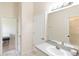 Bright bathroom with a single sink vanity and a mirror; view of the shower through the open door at 32025 Timberlake Dr, Mount Dora, FL 32757