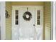 Close-up of the white front door adorned with a decorative wreath and sidelights at 4300 Leafway Cir, Leesburg, FL 34748