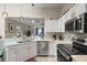 Well-lit kitchen with stainless steel appliances, sleek white cabinets, and open access to living area at 4300 Leafway Cir, Leesburg, FL 34748