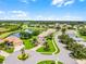 An aerial view of a neighborhood located on a calm lake near an open lush green field at 5620 Illumination Ln, Leesburg, FL 34748