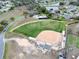 Aerial view of a baseball field with dugouts, stands and green grass in a community setting at 5620 Illumination Ln, Leesburg, FL 34748