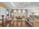 The open living room is anchored by hardwood floors, neutral paint, tray ceiling, and access to an enclosed porch at 5620 Illumination Ln, Leesburg, FL 34748