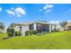 Well-maintained home with a screened lanai, manicured lawn, and lush landscaping at 5620 Illumination Ln, Leesburg, FL 34748