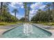 Community entrance showcasing a beautiful water fountain with palm trees and landscaped medians at 5620 Illumination Ln, Leesburg, FL 34748