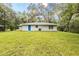 A spacious backyard with lush green lawn, mature trees, and blue back door at 8161 Cr 647, Bushnell, FL 33513