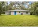 The backyard with lush green lawn, mature trees, and blue back door at 8161 Cr 647, Bushnell, FL 33513