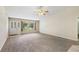 Bright living room featuring neutral carpet, a ceiling fan, and a view of the front yard through large windows at 911 Beverly Harbors Dr # 16, Leesburg, FL 34748