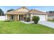 Inviting single-story home with a lush green lawn, colorful landscaping, and a convenient attached two-car garage at 10431 Reagans Run Dr, Clermont, FL 34711