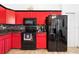 A well-lit kitchen featuring modern appliances, red cabinets, granite countertops, and a stylish backsplash at 10431 Reagans Run Dr, Clermont, FL 34711
