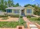 Charming yellow home with blue shutters, complemented by a brick walkway and lush landscaping at 1109 Edmonds St, Leesburg, FL 34748