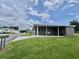 Cozy single-story home with a covered porch, well-kept lawn, and mature trees on a bright, partly cloudy day at 117 Jacaranda Dr, Leesburg, FL 34748