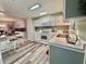 Updated kitchen with white cabinets, laminate floors, and an adjacent dining area at 117 Jacaranda Dr, Leesburg, FL 34748