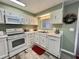 Fully equipped kitchen with white appliances, laminate flooring, and a window view at 117 Jacaranda Dr, Leesburg, FL 34748