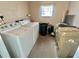 Functional laundry room with washer, dryer, and shelving for storage and organization at 117 Jacaranda Dr, Leesburg, FL 34748
