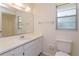 Bathroom featuring white vanity, white toilet, framed mirror, and a window for natural light at 12 Windtree Ln # 202, Winter Garden, FL 34787