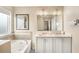 This bright bathroom features double sinks, large mirror, bath, and tile surround at 12120 Sumter Dr, Orlando, FL 32824