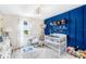 This delightful Bedroom features a bright blue accent wall, a white crib, and a cozy, plush rug at 12120 Sumter Dr, Orlando, FL 32824