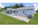 Backyard view of a home with a sunroom, paver patio, and air conditioning unit, surrounded by a green lawn at 1225 Zapata Pl, The Villages, FL 32159