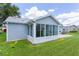 Exterior shot of a sunroom addition with large windows and a patio, attached to a light blue home at 1225 Zapata Pl, The Villages, FL 32159