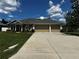 Charming single story home featuring a 3-car garage, manicured lawn, and American flag at 13109 Laurel Crest Ct, Grand Island, FL 32735