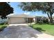 Attractive one-story home featuring a well-maintained lawn, elegant landscaping, and a spacious driveway leading to an attached garage at 1412 Forest Acres Dr, The Villages, FL 32162