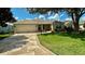 Charming single-story home featuring a manicured lawn, stone driveway, and attached two-car garage at 1412 Forest Acres Dr, The Villages, FL 32162