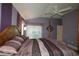 Four-poster bed in a main bedroom with large windows and calm purple walls at 1412 Forest Acres Dr, The Villages, FL 32162
