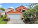Charming orange two-story home with a two car garage and tropical landscaping at 167 Castaway Beach Way, Kissimmee, FL 34746