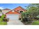 Charming orange two-story home with a two car garage and tropical landscaping at 167 Castaway Beach Way, Kissimmee, FL 34746