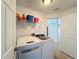 Bright laundry room featuring modern washer and dryer, storage shelves, and tile flooring at 167 Castaway Beach Way, Kissimmee, FL 34746